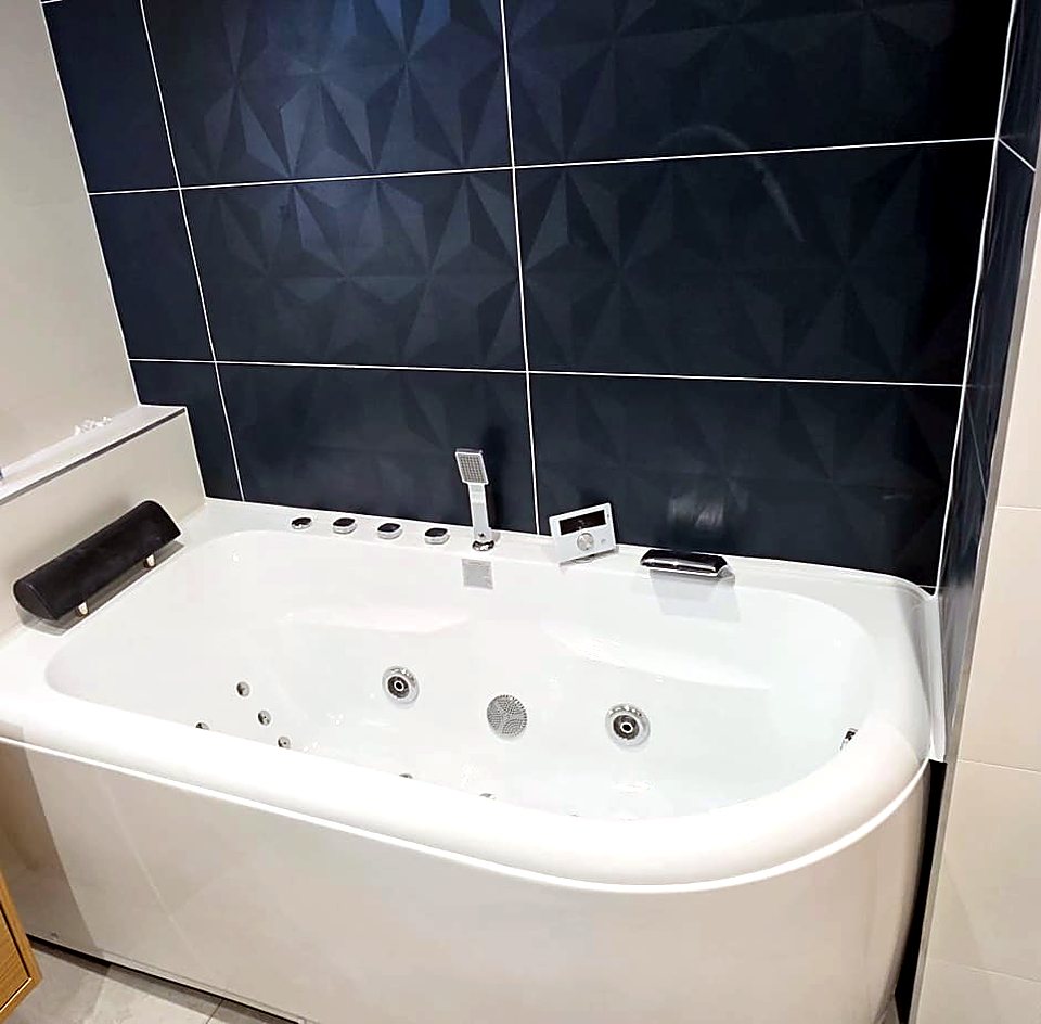 Salle de bain avec baignoire balnéo et carrelage bleu marine à relief